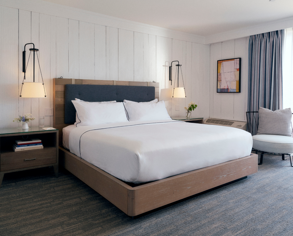 A well-arranged bed with two glowing lamps mounted on both sides and a portrait on the right wall.