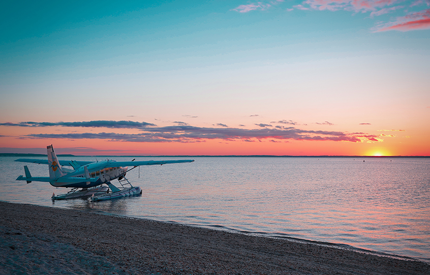 A seaplane parked at the seashore with a wonderful view of the sunset.