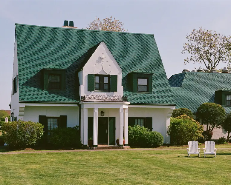 The white and green painted cottage gleams beautifully in the sunlight.