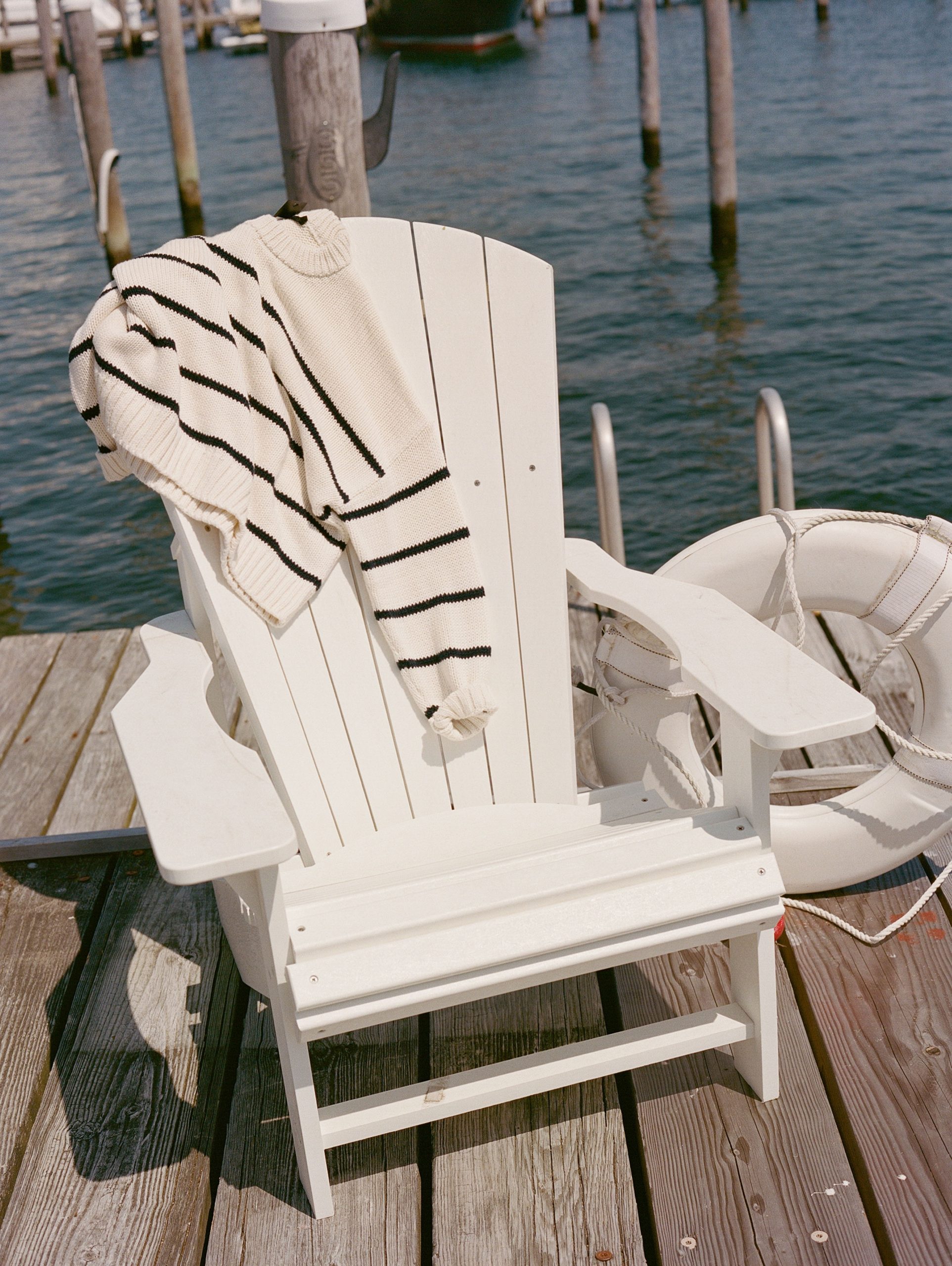 A white sweater with black lines lies on a chair at the dockyard.