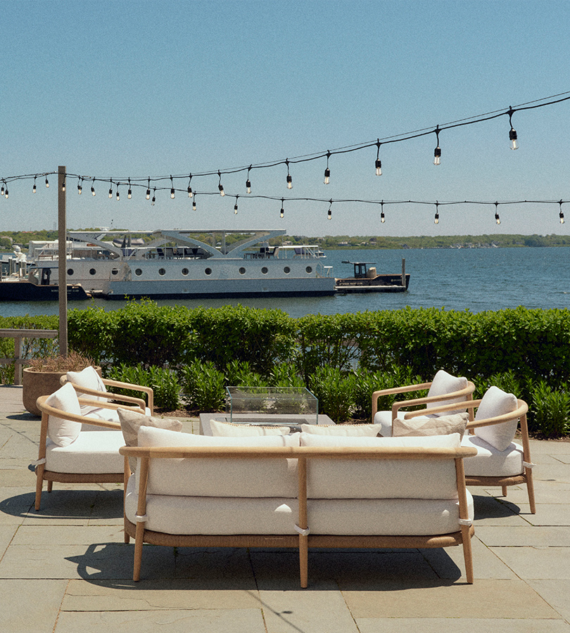 Seating and a table are arranged at the dockyard, offering a splendid view of the ocean.