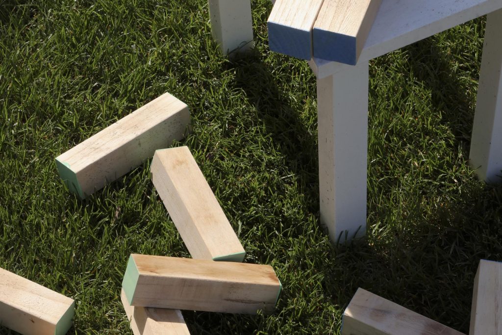 Wooden blocks are resting on the grassy ground next to the table.