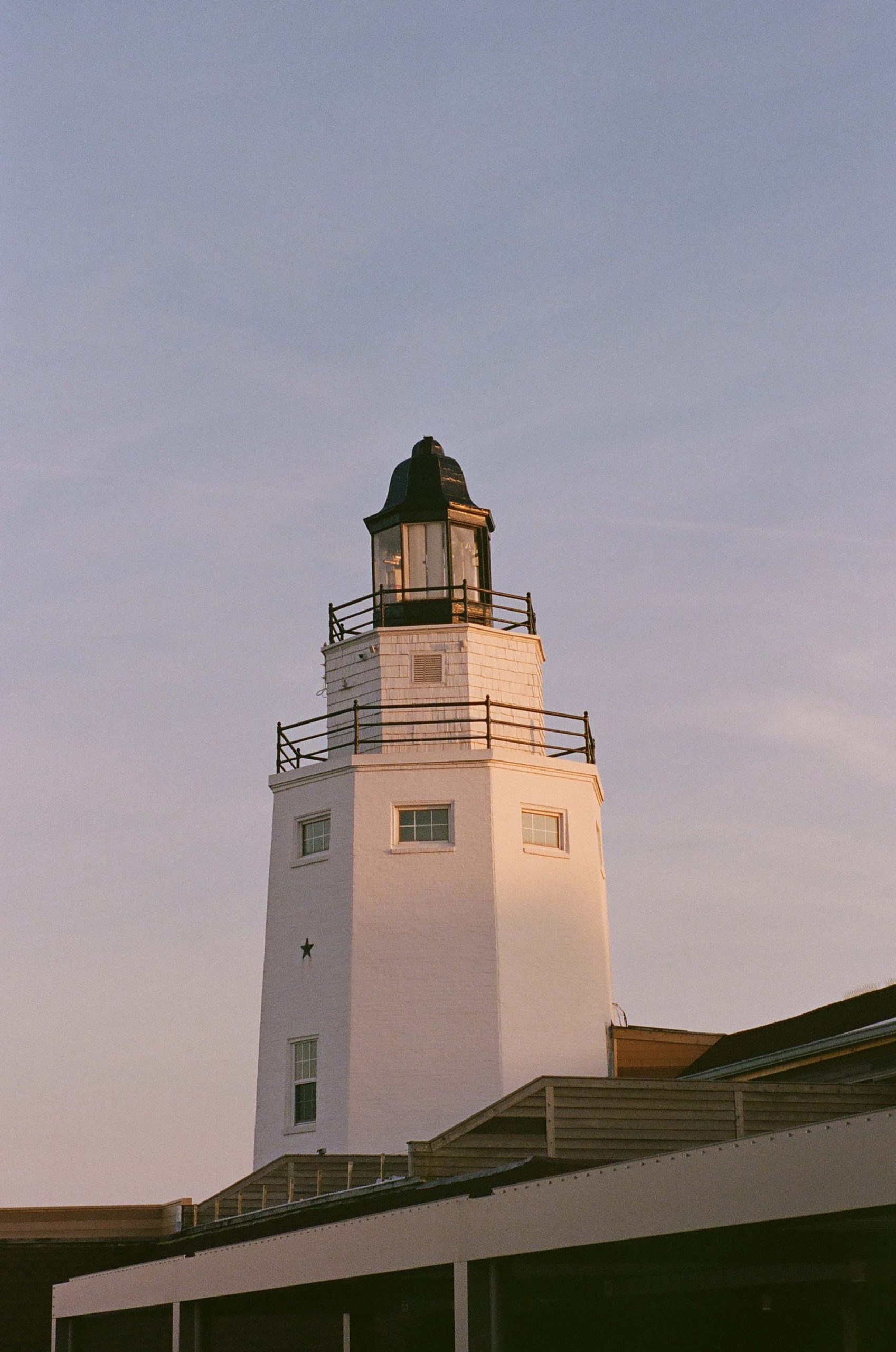 The top edge of a lighthouse glows with the rays of the sun.
