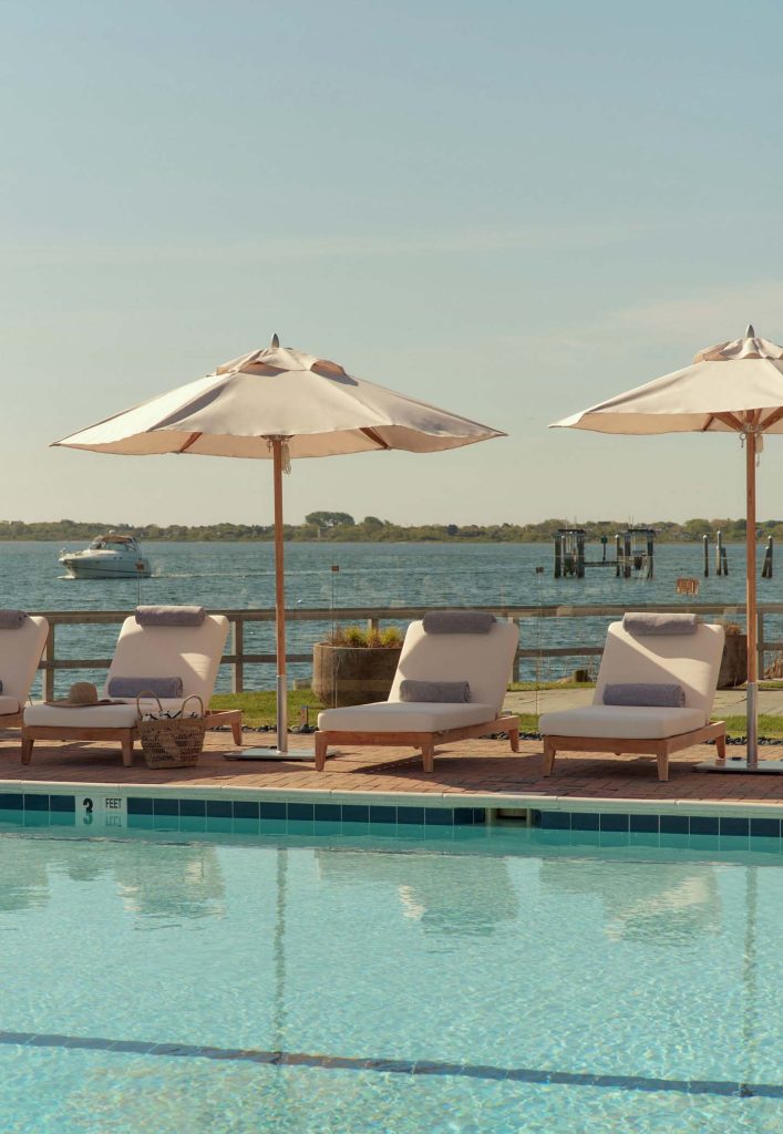 Several lounge chairs are positioned beside the pool, offering a splendid view of the sea.