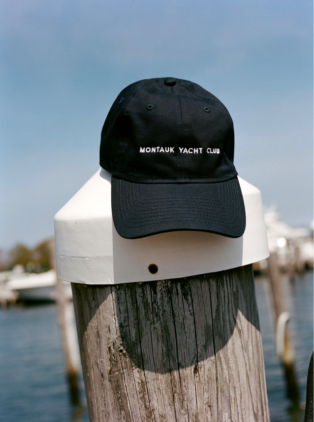 A black cap with the name tag "MONTAUK YACHT CLUB" placed on a pillar by the dockyard ramp.