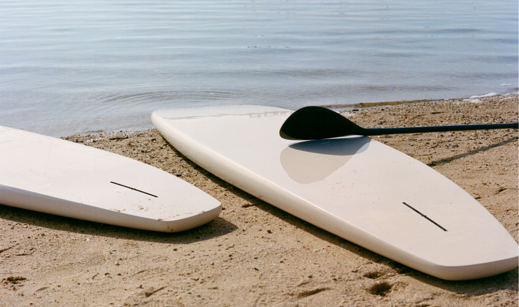 Two surfboards rest on the seashore's edge near the sea.