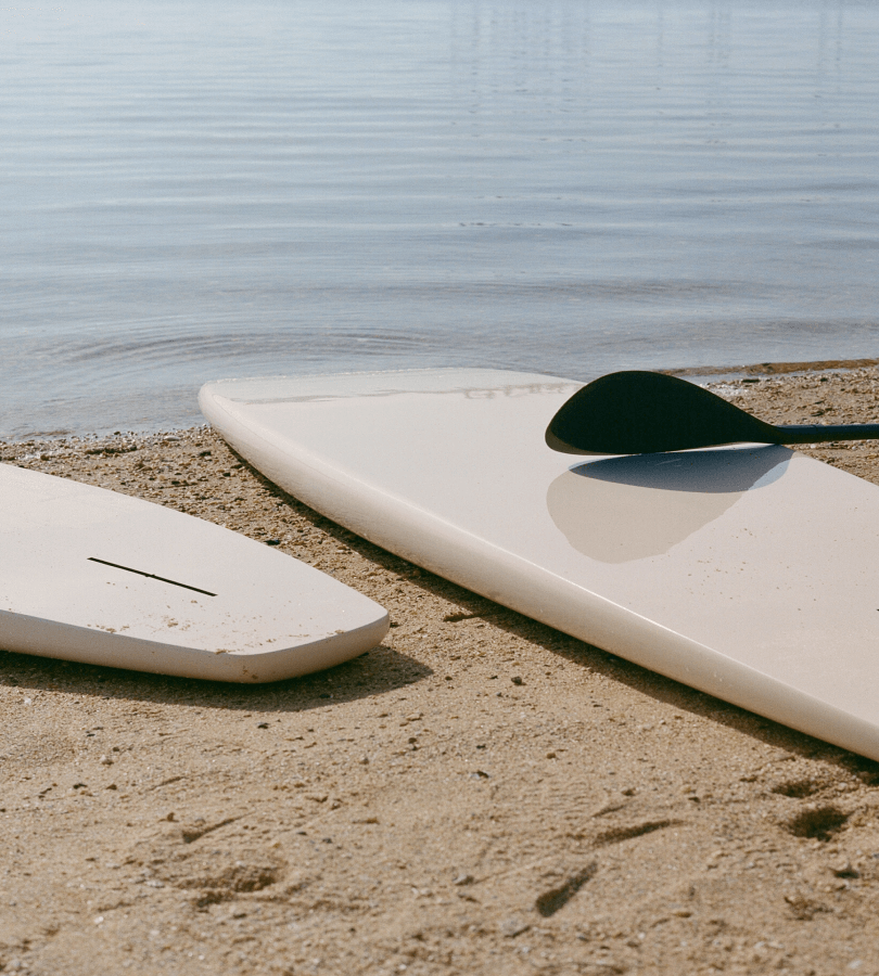 Two surfboards lie on the shore's edge, close to the sea.