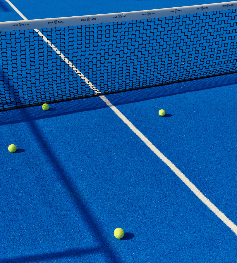A tennis court with a net and tennis ball lying on the ground.