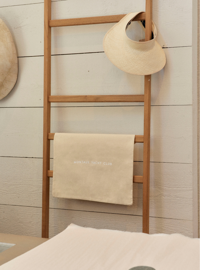 A small towel and a hat placed on the ladder next to the wall.