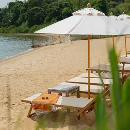 Lounge chairs and umbrellas on sandy lakeside beach with calm water